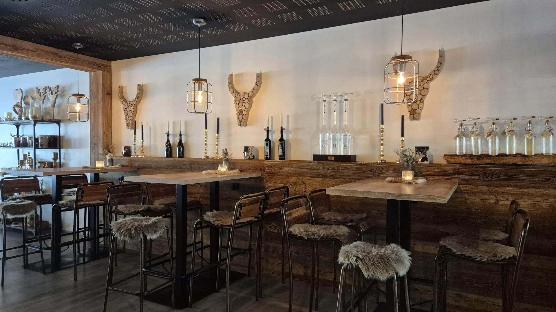 Moderne Bar mit Holztheke, Sitzplätzen und dekorativen Geweihen.