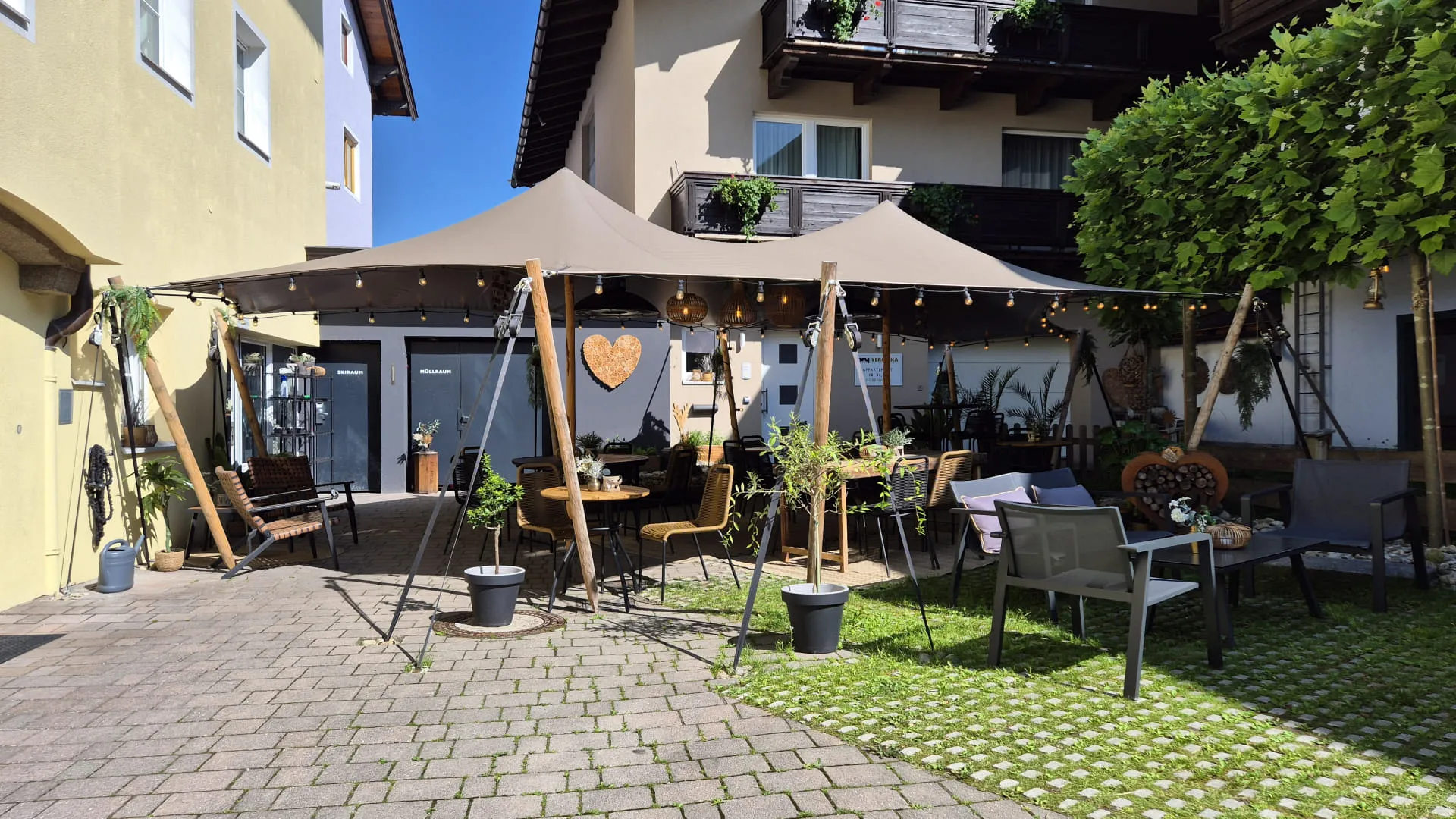 Ein begrüntes Außencafé mit Sonnenschirmen und gemütlichen Sitzplätzen.